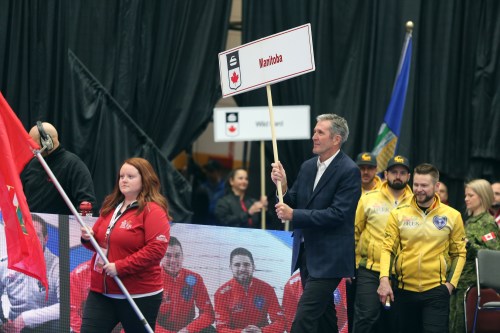 Melissa Verge/The Brandon Sun
Premier Brian Pallister carries out the Team Manitoba sign during the Tim Hortons Brier on Monday afternoon at the Keystone Centre. Team Manitoba, dressed in yellow, followed.