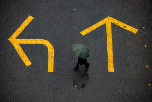 A person carrying an umbrella walks past directional arrows painted on the road as rain falls in Vancouver, on Sunday, December 27, 2020.British Columbia should be well into its rainy season, but persistent hot and dry weather has created drought conditions.THE CANADIAN PRESS/Darryl Dyck