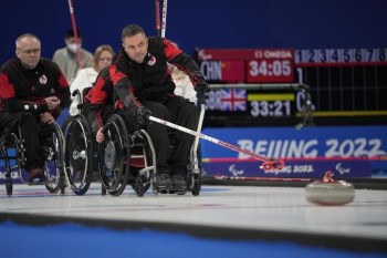 Canada's Mark Ideson pushes a stone as he and his teammates play against Norway during their wheelchair curling competition at the 2022 Winter Paralympics, Thursday, March 10, 2022, in Beijing. THE CANADIAN PRESS/AP-Dita Alangkara