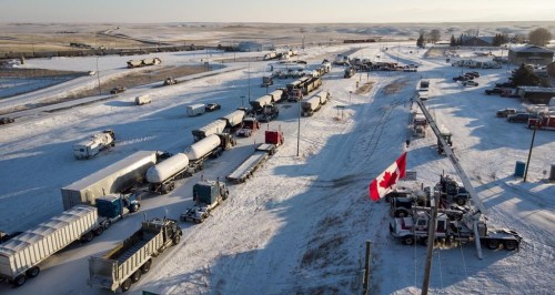 A truck convoy of anti-COVID-19 vaccine mandate demonstrators blocks the highway at the busy Canada-U.S. border crossing in Coutts, Alta., Wednesday, Feb. 2, 2022. THE CANADIAN PRESS/Jeff McIntosh