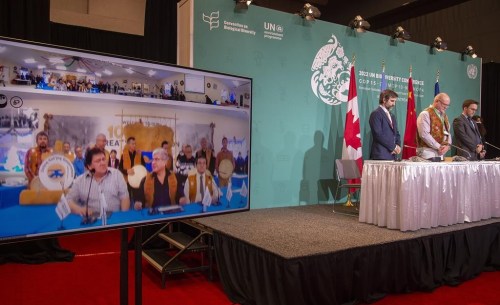 Minister of Environment and Climate Change Steven Guilbeault, left, and Northwest Territories MLA for Nahendeh Shane Thompson bow during a prayer performed via videoconference and shown on screen during a news conference at the COP 15 summit on biodiversity, in Montreal, Saturday, Dec. 17, 2022. THE CANADIAN PRESS/Peter McCabe