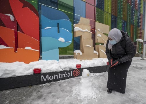 Amel Ibrahem, a delegate from Sudan, examines her first ever snowman which she built during a break from the COP 15 summit on biodiversity, in Montreal, Saturday, Dec. 17, 2022. THE CANADIAN PRESS/Peter McCabe