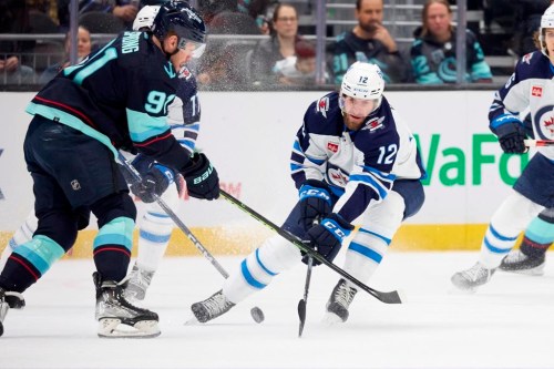 Seattle Kraken right wing Daniel Sprong battles for the puck with Winnipeg Jets center Jansen Harkins (12) during the first period of an NHL hockey game, Sunday, Dec. 18, 2022, in Seattle. (AP Photo/John Froschauer)