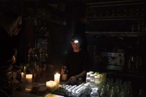 A bartender prepares a drink using a headlamp at a restaurant illuminated by candle lights during a power outage in Kyiv, Ukraine, Saturday, Dec. 17, 2022. (AP Photo/Felipe Dana)