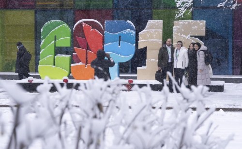 Delegates take souvenir photos during a snowfall outside the convention centre at the COP15 UN conference on biodiversity in Montreal, Friday, Dec. 16, 2022. THE CANADIAN PRESS/Paul Chiasson