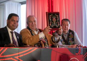 Manitoba Métis Federation President David Chartrand (middle) holds up a copy of the Red River Métis self-government treaty during a signing ceremony in Winnipeg on Nov. 30. Also pictured are federal Crown-Indigenous Relations Minister Gary Anandasangaree (left) and Red River Métis lead negotiator Allan Benoit. (Brook Jones/Winnipeg Free Press)