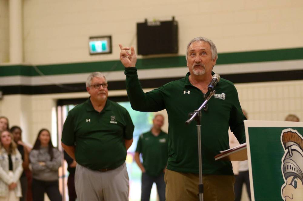 Carey Lasuik, right, points to the banners lining the Neelin gymnasium walls while recognizing the coach he worked alongside for 12 years of varsity basketball. (Thomas Friesen/The Brandon Sun)