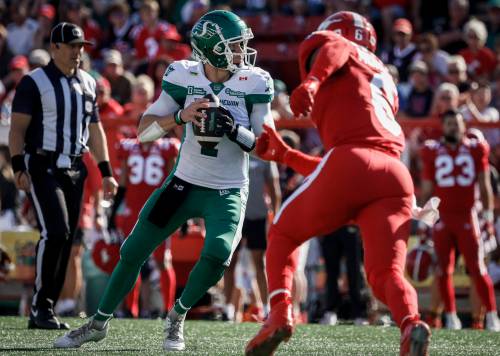 Saskatchewan Roughriders quarterback Trevor Harris, left, looks for a receiver as the Calgary Stampeders’ Derrick Moncrief closes in during CFL football action in Calgary on Aug. 23. Bruce Penton has pencilled in Roughriders versus Stampeders for the Western final. (The Canadian Press files)