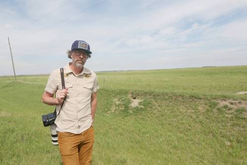 Tim Smith, The Brandon Sun&rsquo;s only photojournalist, is seen outside a fox den near Brandon in June. Smith photographed several kits and their mother at the den this spring after waiting more than three hours. He said he returns to about a dozen dens in the area every year. (Connor McDowell/The Brandon Sun)