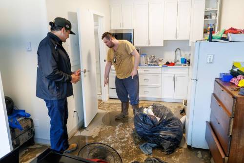 Manitoba Premier Wab Kinew meets Dauphin resident David McRae as he cleans out his apartment between shifts on Thursday. McRae was at home when water started coming in through his front door. (Mike Deal/Winnipeg Free Press)